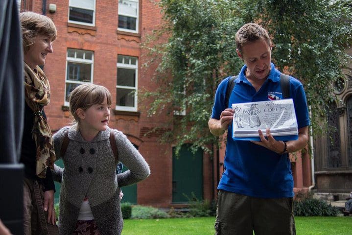 A young girl and her mom look on as a tour guide provides information on a Secrets of Old London Tour with Tripadvisor.