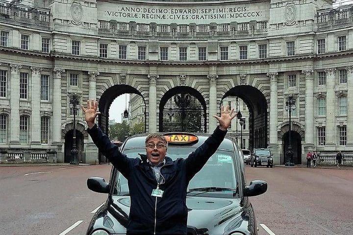 A London tour guide sits on the hood of an iconic London taxi.