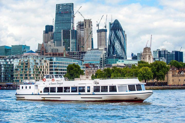 A boat cruises along a river in London on a tour.