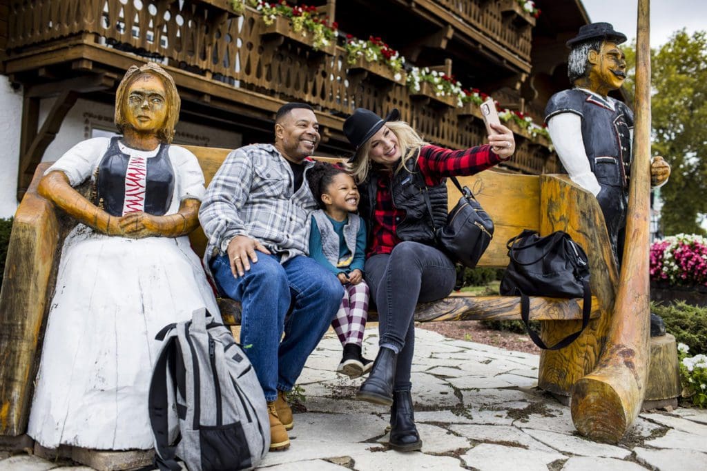 A family takes a selfie with a Swiss-inspired bench outside of a chalet in New Glarus.
