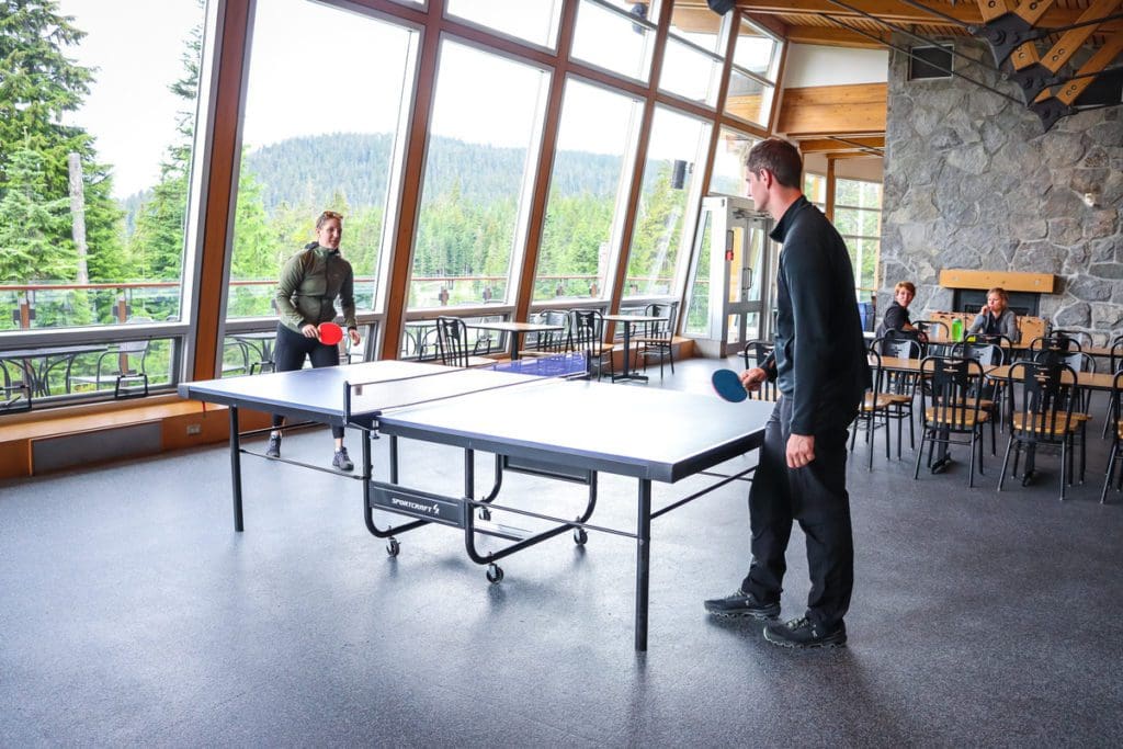 Inside a game area at Whistler Olympic Park, where two people are playing ping pong.