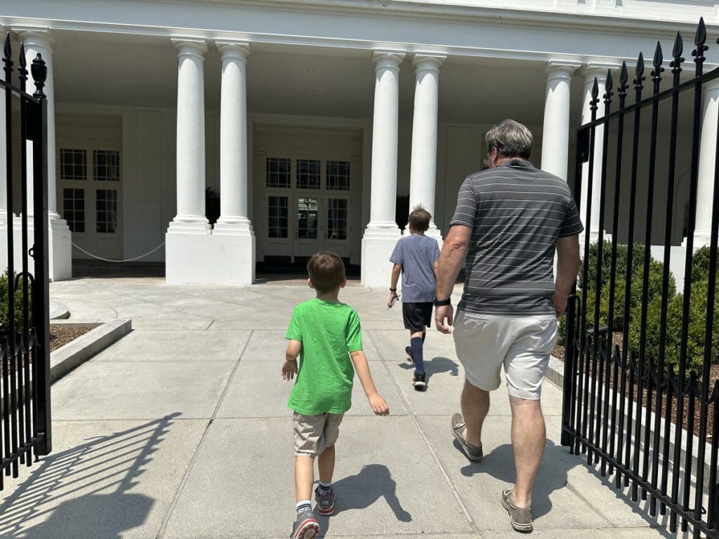 A dad and his two young sons walk into the White House for a tour of the grounds.