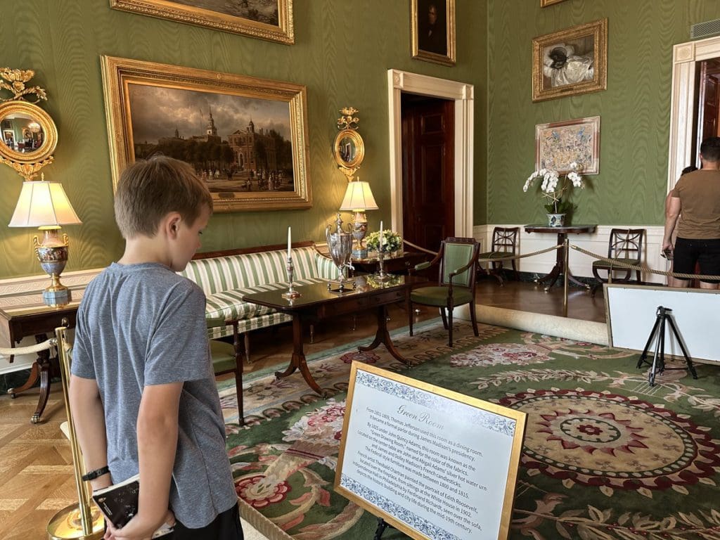 A young boy reads a museum plaque while touring the White House.