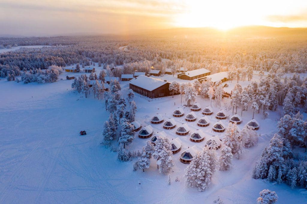 An aerial view of the lodge and cabins at Wilderness Hotel Inari at sunrise at one of the best Finland hotels for families.