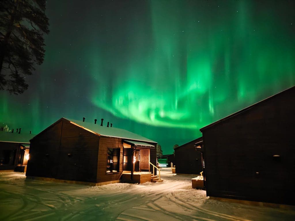 A cabin at Wilderness Hotel Inari with the northern lights above it.