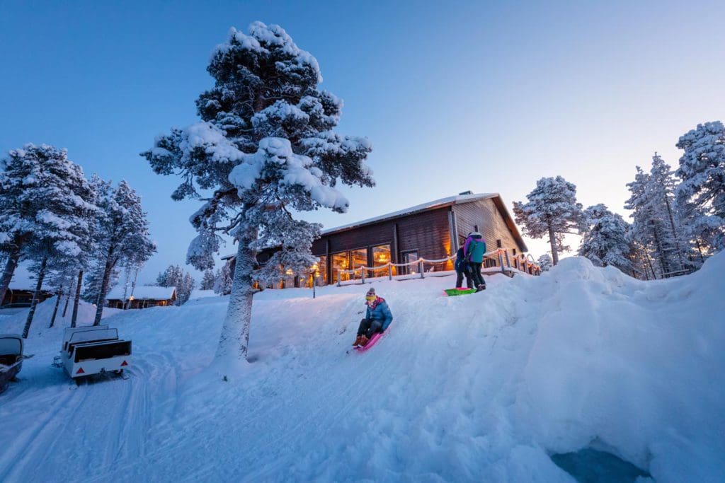 Kids go sledding, while staying at Wilderness Hotel Inari, one of the best Finland hotels for families.