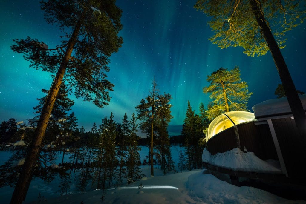 An igloo at Wilderness Hotel Nellim, with the northern lights overhead.