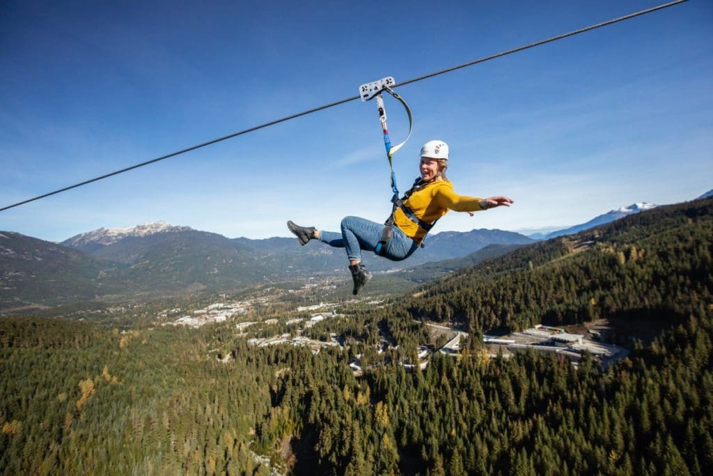 A woman ziplines through the air with Ziptrek Ecotours Inc.