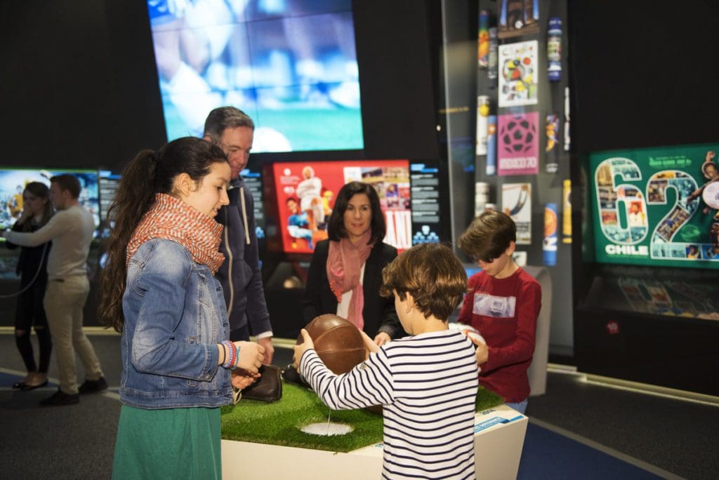 A family of five explores an exhibit at the FIFA World Football Museum.