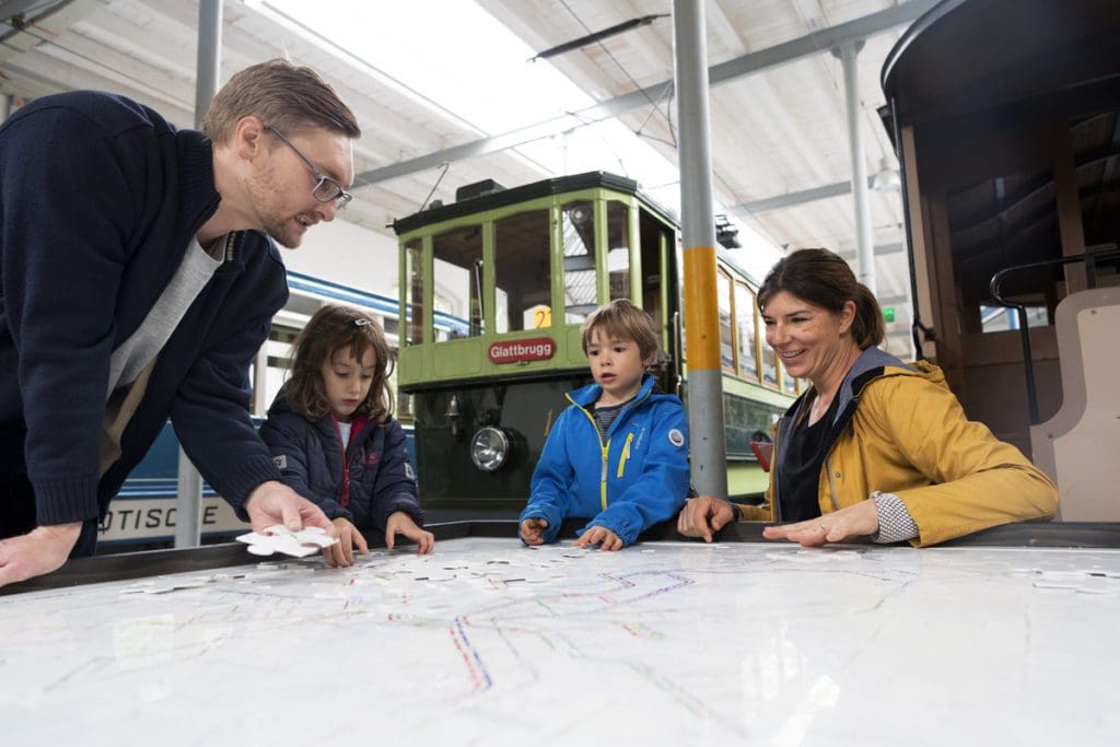 A family of four looks at tram maps at the Zürich Tram Museum.