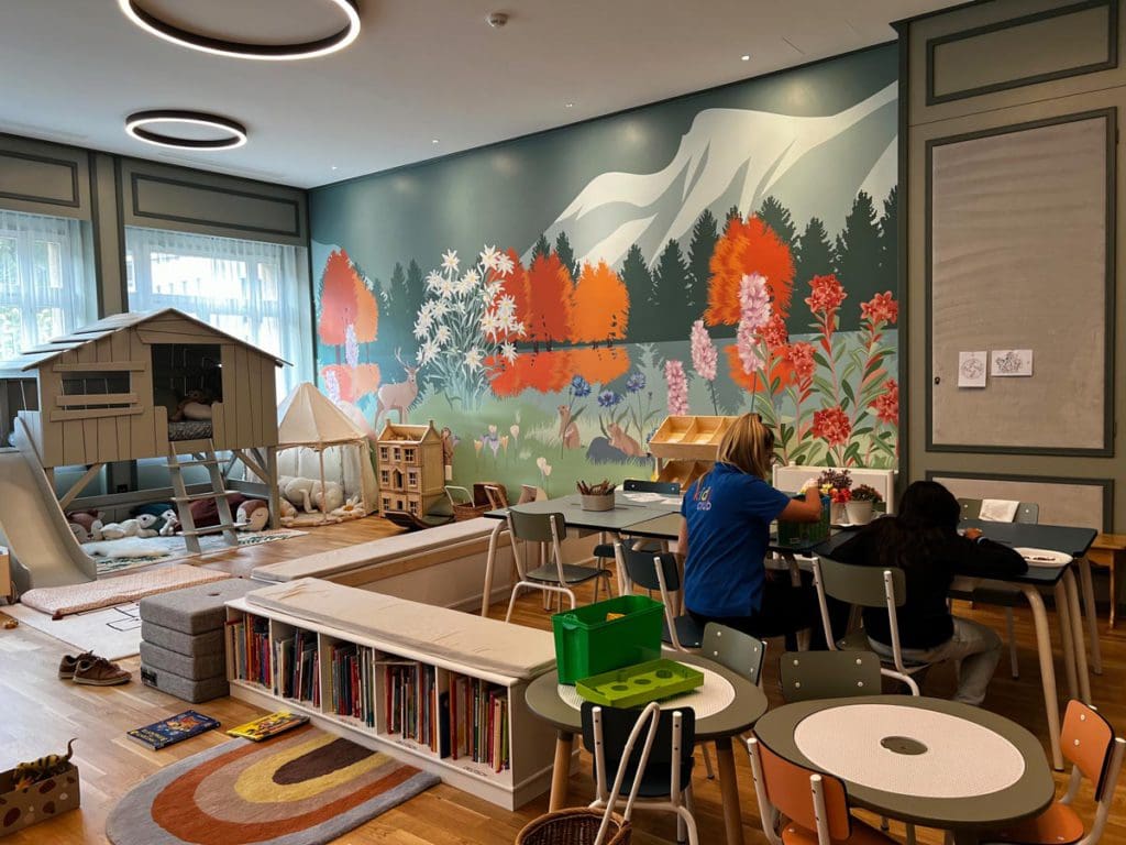 A young girl works on a craft activity with a staff member at the kids' club at Kulm Hotel, one of the things you'll learn about in this review of Kulm Hotel St. Moritz.