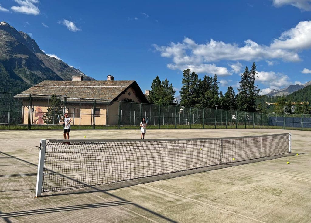 Two kids play tennis in the summer at Kulm Hotel St. Moritz, one of the things you'll learn about in this review.