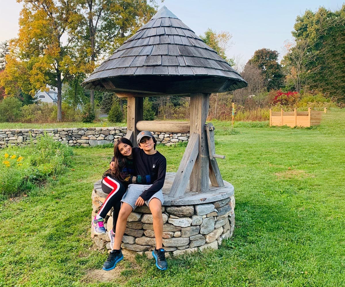 Two kids sit together at the edge of a well in Litchfield, Connecticut.