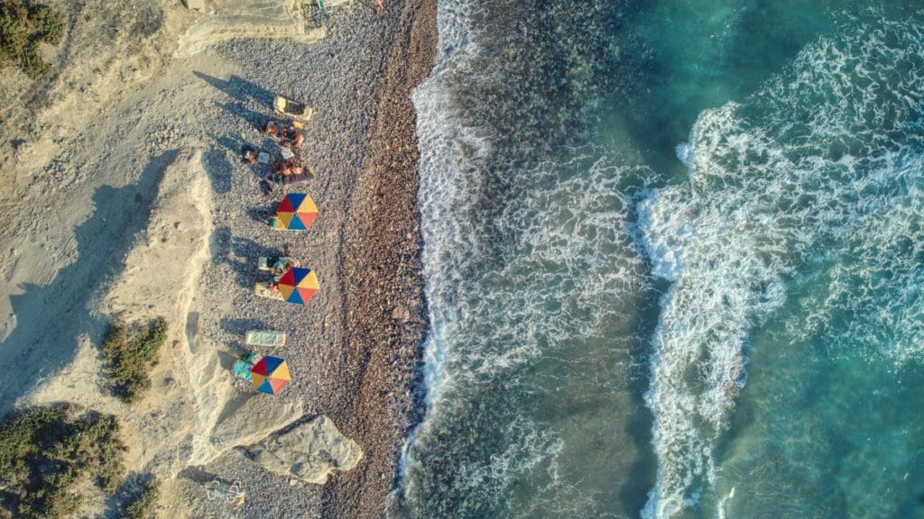 An aerial view of a row of beach umbrellas on a beach in Kos, Greece.