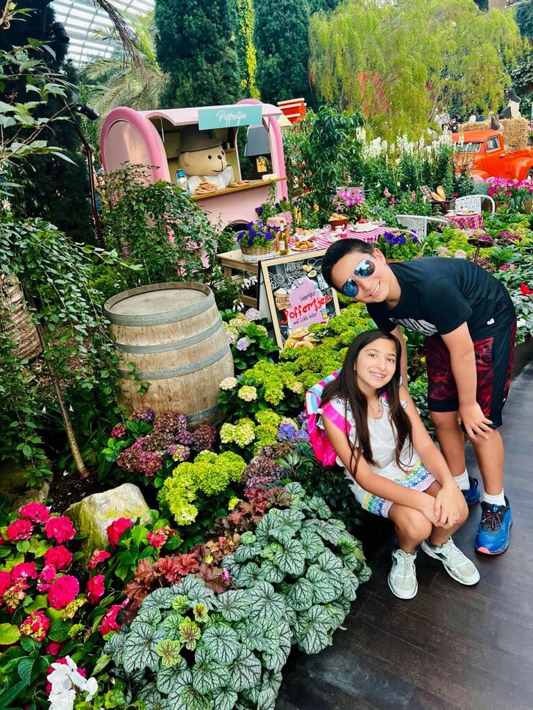 Two kids pose together near flowers at a garden in Singapore, one of the best places to visit in Asia with kids.