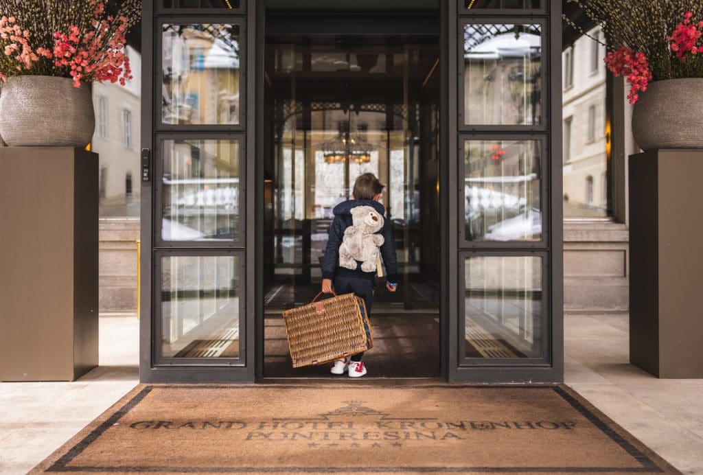 A little boy with a suitcase walks into Grand Hotel Kronenhof.