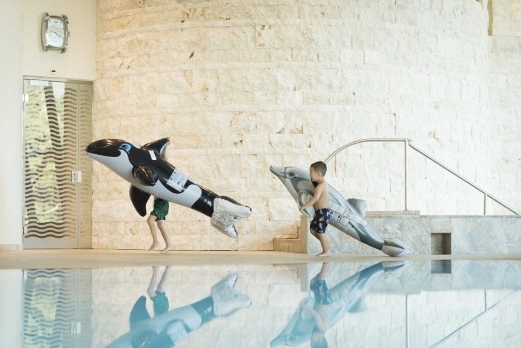 Two kids play with large inflatables at the pool at Grand Hotel Kronenhof.