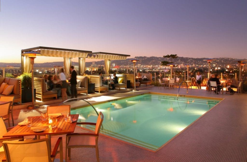 The outdoor pool, with lush seating and an evening view of downtown, at Kimpton Hotel Wilshire.