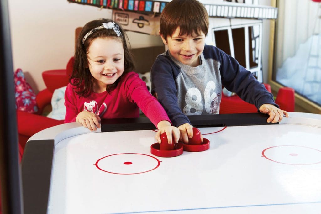 Two kids play air hockey, while staying at Nira Alpina.