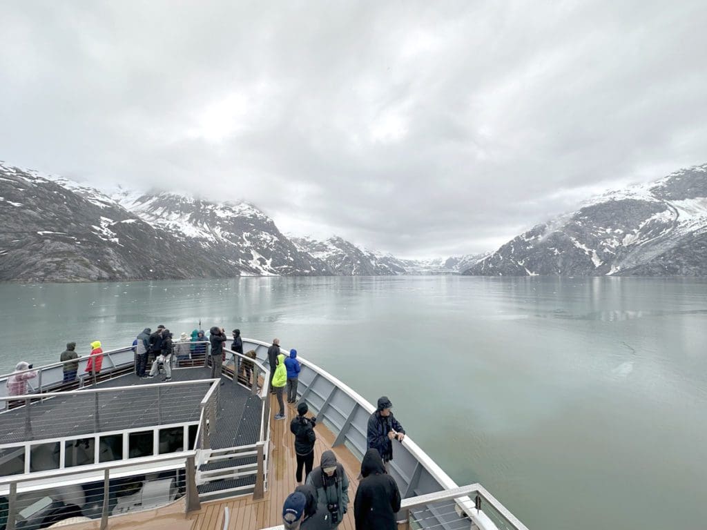 A family looks out onto an Alaskan scene from their cruise ship.