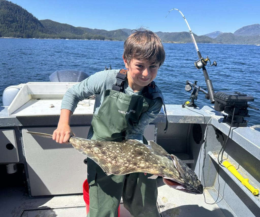 A young boy holds a fish he caught, while exploring Alaska as a family.