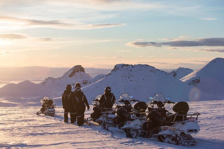 Packed snowmobiles and their riders, taking a rest while exploring on the Golden Circle & Glacier Snowmobiling Day Trip from Reykjavik, one of the best Iceland tours with kids.