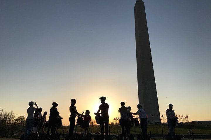Several people on segways below the Washington Monument at dusk while on the Washington DC "See the City" Guided Sightseeing Segway Tour.