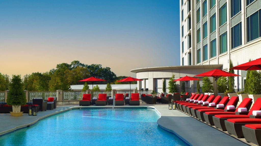 The outdoor pool, with red pool chairs surrounding it, at Intercontinental Buckhead Atlanta, an IHG Hotel.