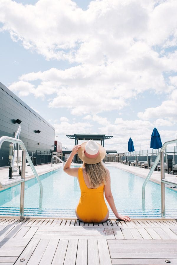 A woman in a yellow bathing suit sits poolside at Intercontinental Washington DC The Wharf, an IHG Hotel.