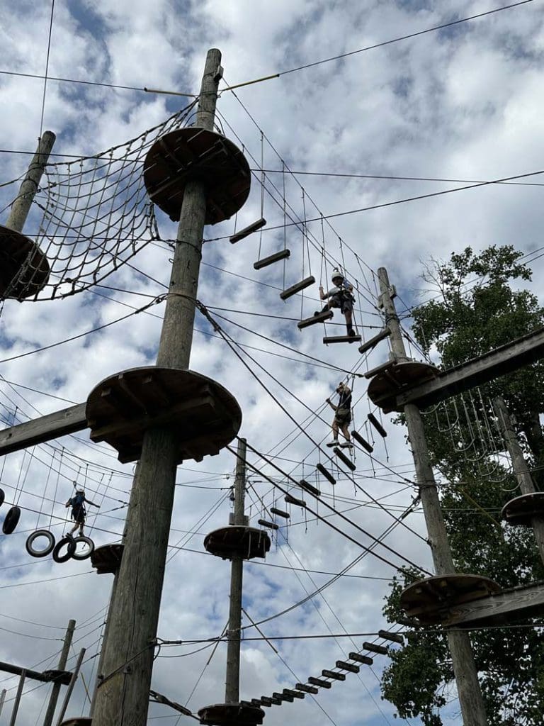 Several children climb along a ropes course.