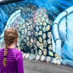 A young girl looks at a mural in East Berlin.