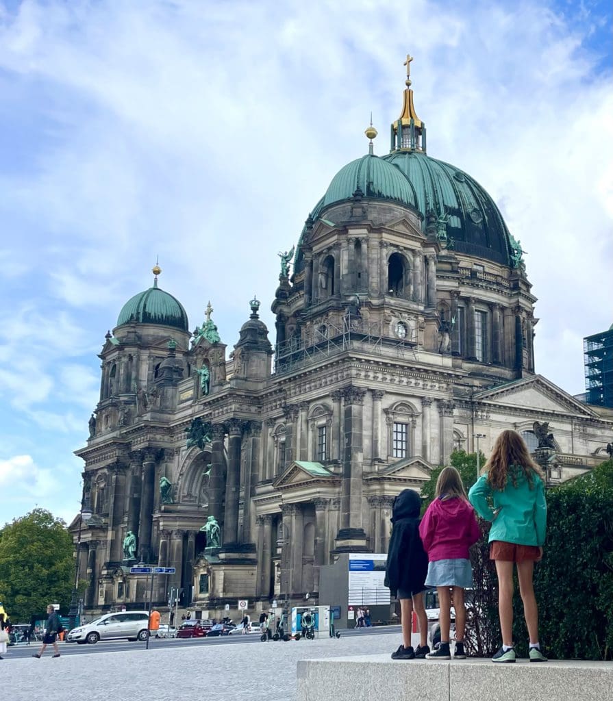 Three kids stand together while looking at Museum Island.