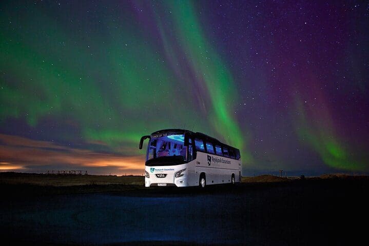 A bus that leads the Northern Lights Tour from Reykjavik rests under the northern lights.