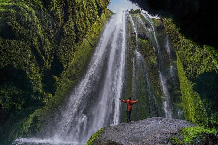 A man in red takes in a view of a waterfall on the South Coast of Iceland Private Day Trip by SUV or Van.