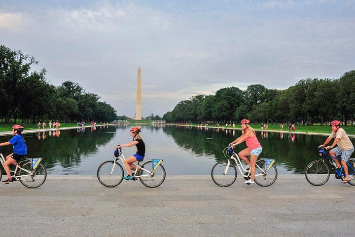A family of four bikes in front of the Washington monument while on the Washington DC Capital Sites Bike Tour.