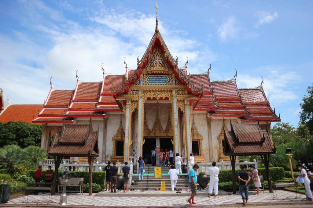 People walking near a Temple in Phuket, Thailand, one of the best hot places to visit in December for families.
