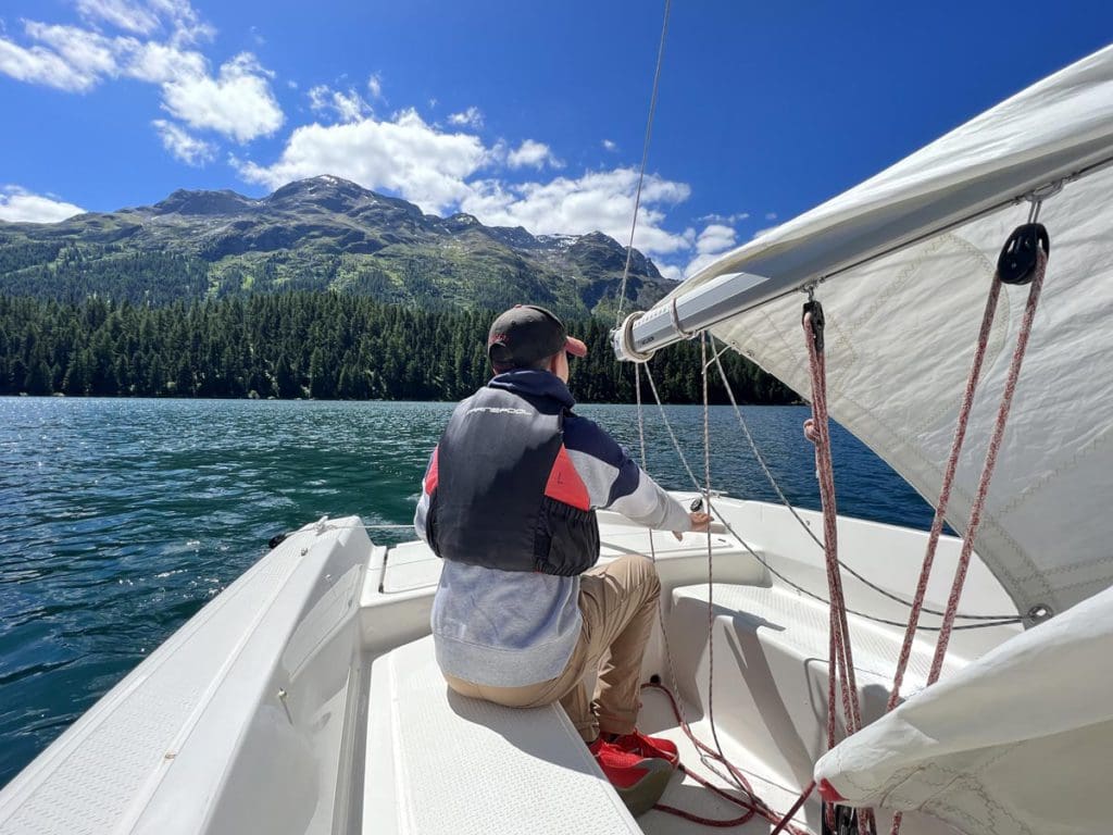 A young boy learns to sail on Lake Moritz, a must on any St Moritz Itinerary with kids.