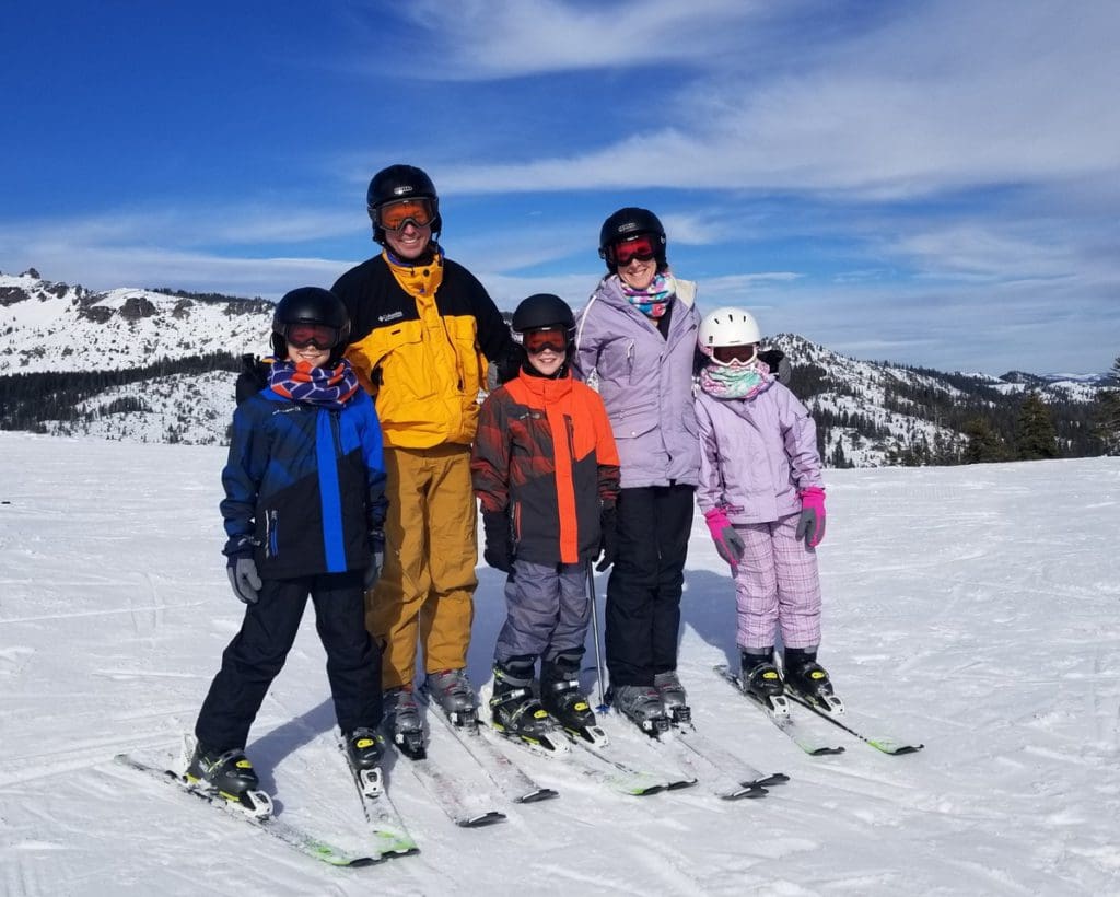 A family on skis enjoys a sunny day in Lake Tahoe, while on a ski vacation to Lake Tahoe with kids.