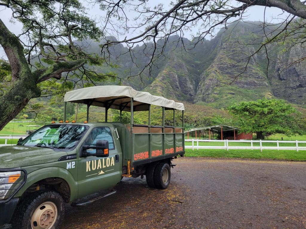 A parked jeep for Kualoa Ranch & Private Nature Reserve, with spectacular scenery behind it.