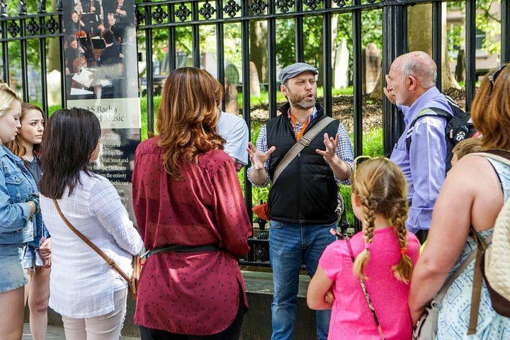 A guide provides information to a family group on the All-Access 9/11: Ground Zero Tour, Memorial and Museum, One World Observatory.