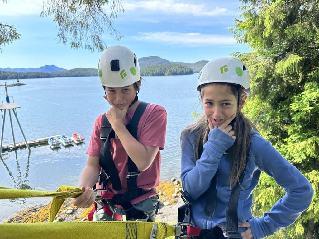 Two kids stand together preparing for an outdoor adventure in Alaska.