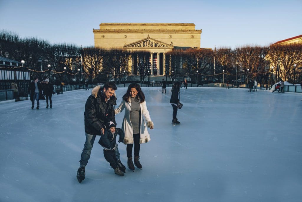 A family of three ice skates in Washington DC, one of the best budget-friendly Christmas destinations in the US for families.