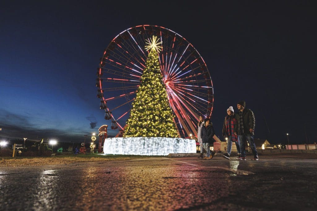 A family enjoys a large Christmas tree in front of the huge Branson Ferris Wheel.