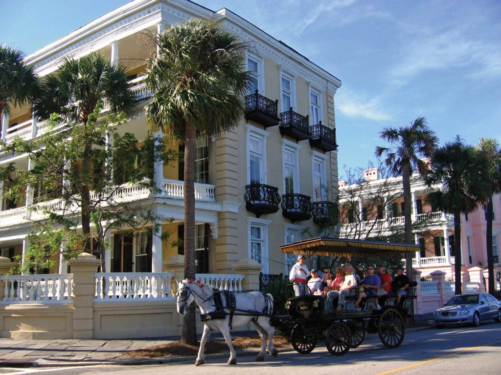 A horse-drawn carriage carrying people through historic Charleston.