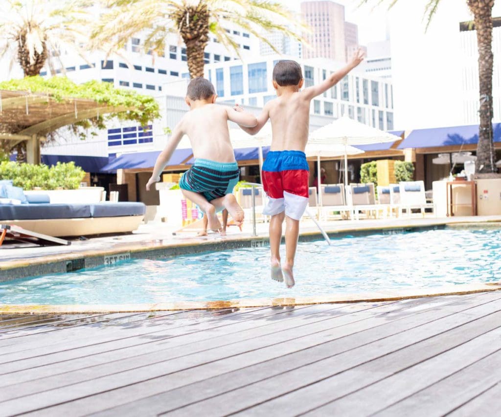 Two kids jump into the outdoor pool at Four Seasons Hotel Houston.
