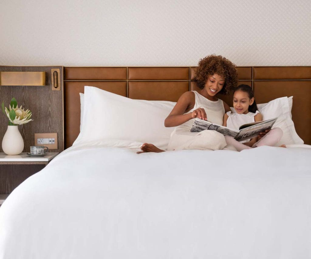 Mother and daughter cuddle up and read a book together, while staying at the Four Seasons Hotel Houston.