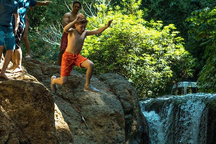 Kids jumping into a pool on the Full-Day Waterfall Adventure.