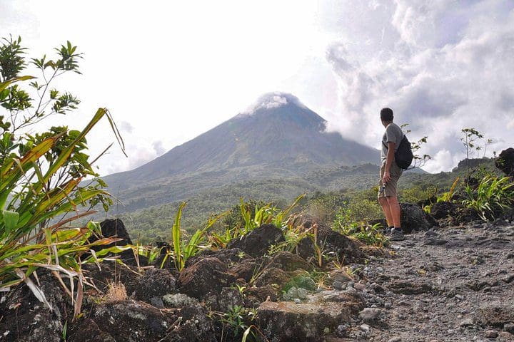 A hiker enjoys a view of a volcano on the Full-Day Arenal Volcano, La Fortuna Waterfall and Hotsprings tour.
