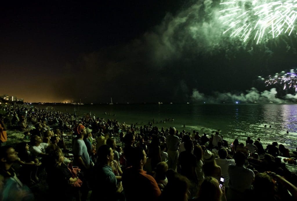 A crowd watching New Year's Eve fireworks on a beach near Miami, one of the best places to celebrate the New Year on the East Coast.