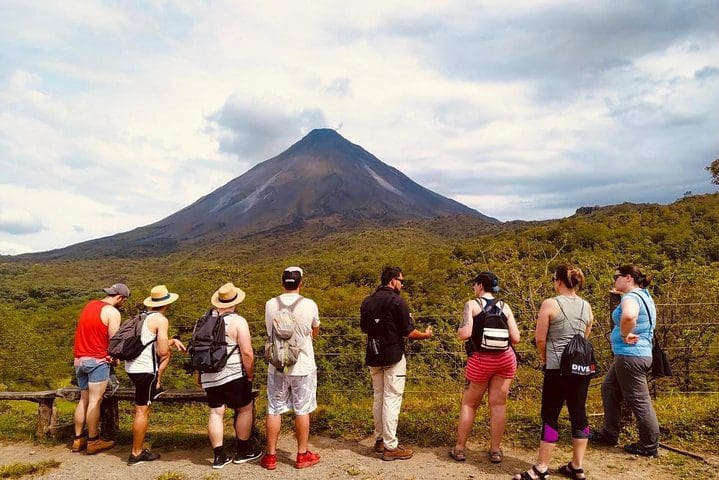 A tour group enjoys a view of a volcano on the Hanging Bridges, La Fortuna Waterfall, and Arenal Volcano Hike tour.